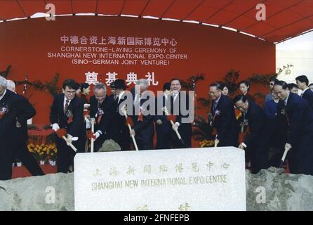 „Bundeskanzler Gerhard Schröder beim Spatenstich für den Bau der Messe in Shanghai. Dieses Projekt ist ein Joint Venture zwischen der Shanghai Lujiazui Development Group und der German Exposition Corporation Internation (GEC). Im Hintergrund ist die "Cornerstone-Leying Ceremony of Shanghai New International Expo Center (Sino-German Joint Venture). [Automatisierte Übersetzung]' Stockfoto