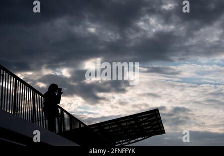 Hamburg, Deutschland. Mai 2021. Eine Frau blickt mit einem Fernglas auf den Hafen vor einen wolkenlosen Himmel. Quelle: Daniel Bockwoldt/dpa/Alamy Live News Stockfoto