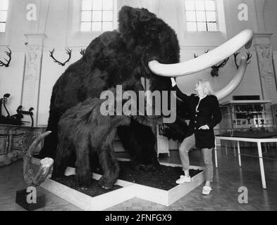 Nachbildung eines wolligen Mammuts mit jungen Menschen in einer Ausstellung über die Jagd in der Steinzeit im Weißen Saal des Museums. [Automatisierte Übersetzung] Stockfoto