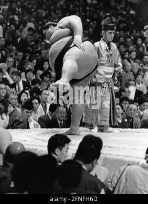 Ein Sumo-Wrestler, der Dohyo-iri, die Ring-Einführungszeremonie in Osaka, vorführt. Neben ihm ist der Gyoji, einer der Richter. Im Hintergrund sind die Zuschauerstände zu sehen. [Automatisierte Übersetzung] Stockfoto