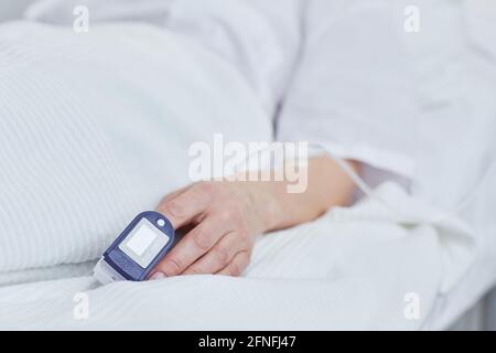 Nahaufnahme des Patienten, der mit medizinischen Druckgeräten auf dem Bett liegt An ihrem Finger Stockfoto