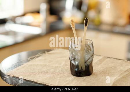 Glas mit zwei umweltfreundlichen Bambus-Zahnbürsten auf Tisch mit Witgh bedeckt Leinenstoff Stockfoto