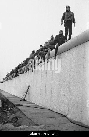 Berlin-City / Mitte / DDR / Berliner Mauer 12.11.1989 Potsdamer Platz. Die Mauer wird von DDR-Grenzsoldaten einer Stasi-Einheit abgerissen. Die Berliner sind auf die Mauer geklettert, um eine bessere Aussicht zu bekommen. // Vereinigung / Volksarmee / DDR-Grenzposten / Geschichte / Kommunismus / Tiergarten Stockfoto