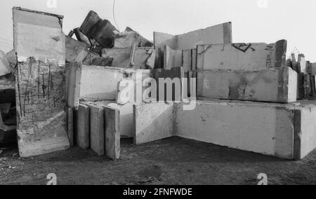 Berlin-Bezirk / DDR / Berliner Mauer 3 / 1991 Treptow: Überall in der Stadt wird die Mauer abgerissen, die Betonelemente werden irgendwo gelagert, hier am Stadtrand von Groß-Glienicke. Bunt bemalte Stücke werden an Sammler verkauft, aber die meisten von ihnen werden zu Baumaterial geschreddert. Symbol für das Ende der DDR, das Ende der antifaschistischen Mauer. // Sozialismus / Wiedervereinigung / Geschichte / Kommunismus [automatisierte Übersetzung] Stockfoto