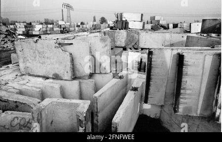 Berlin-Bezirk / DDR / Berliner Mauer 3 / 1991 Treptow: Überall in der Stadt wird die Mauer abgerissen, die Betonelemente werden irgendwo gelagert, hier am Stadtrand von Groß-Glienicke. Bunt bemalte Stücke werden an Sammler verkauft, aber die meisten von ihnen werden zu Baumaterial geschreddert. Symbol für das Ende der DDR, das Ende der antifaschistischen Mauer. // Sozialismus / Wiedervereinigung / Geschichte / Kommunismus [automatisierte Übersetzung] Stockfoto