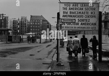 Berlin-Bezirke / DDR-Mauer / 1985 Checkpoint Charly. Der Grenzübergang zwischen Kreuzberg und Mitte ist für Ausländer, darunter Diplomaten, reserviert. Sie werden vom deutschen Zoll, einem Hilfsorgan der Westalliierten, abgeräumt. Zwei Geschäftsleute gehen nach Ost-Berlin. Am Checkpoint Charly standen sich amerikanische und sowjetische Panzer während des Mauerbaus 1961 gegenüber. Viersprachiges Zeichen der 4 Alliierten: Sie verlassen den amerikanischen Sektor // Berliner Status / Checkpoint / Grenze / Bezirke / // Geschichte / Alliierten / Kommunismus / Sowjets [automatisierte Übersetzung] Stockfoto