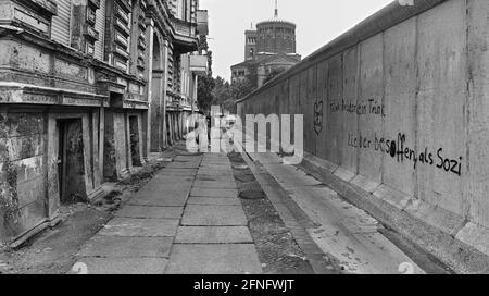 Berlin-City / Kreuzberg / 25.7.1981 die Mauer an der Heckertstraße / Koepenicker Straße, hinten die Thomaskirche. Ost-Berlin beginnt eigentlich an der Hauswand links, aber die DDR hat die Mauer ein wenig zurückgeschoben, so dass die West-Berliner in die Häuser gelangen konnten. Rechts hinter der Mauer befindet sich Ost-Berlin. // Kommunismus / [automatisierte Übersetzung] Stockfoto