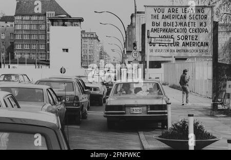 Berlin-Bezirke / DDR-Mauer / 1985 Checkpoint Charly. Der Grenzübergang zwischen Kreuzberg und Mitte ist für Ausländer, darunter Diplomaten, reserviert. Sie werden vom deutschen Zoll, einem Hilfsorgan der Westalliierten, abgeräumt. Zwei Geschäftsleute gehen nach Ost-Berlin. Am Checkpoint Charly standen sich amerikanische und sowjetische Panzer während des Mauerbaus 1961 gegenüber. Viersprachiges Zeichen der 4 Alliierten: Sie verlassen den amerikanischen Sektor // Berliner Status / Checkpoint / Grenze / Bezirke / // Geschichte / Alliierten / Kommunismus / Sowjets [automatisierte Übersetzung] Stockfoto