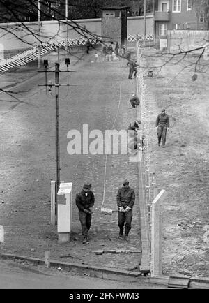 Berlin-Neukoelln / DDR / Mauer / 10 / 1980 DDR-Grenzposten ziehen neuen Stacheldraht entlang der Mauer, der Bouchestrasse zwischen Neukoelln und Treptow. Es wird elektrisch geladen und löst bei Berührung einen Alarm aus. Oben links befindet sich West-Berlin. Die Wand ist weiß gestrichen, um Flüchtlinge hervorstechen zu lassen. Die beiden Grenzposten davor achten darauf, dass die anderen nicht in den Westen fliehen. // Stacheldraht / Grenzbefestigungen / Bezirke [automatisierte Übersetzung] Stockfoto