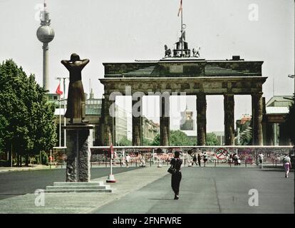 Berlin / DDR / 1984 das Brandenburger Tor. Kein Verkehr. Die Mauer hat die Straßen unterbrochen. Vor einer Gedenkstätte, links hinter dem Fernsehtumr // Mauer DDR-Mauer / Geschichte / Kommunismus Stockfoto