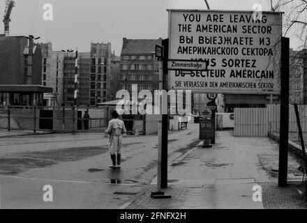 Berlin-Bezirke / DDR-Mauer / 1985 Checkpoint Charly. Der Grenzübergang zwischen Kreuzberg und Mitte ist für Ausländer, darunter Diplomaten, reserviert. Sie werden vom deutschen Zoll, einem Hilfsorgan der Westalliierten, abgeräumt. Zwei Geschäftsleute gehen nach Ost-Berlin. Am Checkpoint Charly standen sich amerikanische und sowjetische Panzer während des Mauerbaus 1961 gegenüber. Viersprachiges Zeichen der 4 Alliierten: Sie verlassen den amerikanischen Sektor // Berliner Status / Checkpoint / Grenze / Bezirke / // Geschichte / Alliierten / Kommunismus / Sowjets [automatisierte Übersetzung] Stockfoto