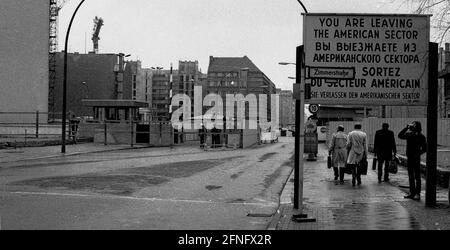 Berliner Bezirke / DDR-Mauer / 1985 Checkpoint Charly. Der Grenzübergang zwischen Kreuzberg und Mitte ist für Ausländer, darunter Diplomaten, reserviert. Sie werden vom deutschen Zoll, einem Hilfsorgan der Westalliierten, abgeräumt. Zwei Geschäftsleute gehen nach Ost-Berlin. Am Checkpoint Charly standen sich amerikanische und sowjetische Panzer während des Mauerbaus 1961 gegenüber. Viersprachiges Zeichen der 4 Alliierten: Sie verlassen den amerikanischen Sektor // Berliner Status / Checkpoint / Grenze / Bezirke / // Geschichte / Alliierten / Kommunismus / Sowjets [automatisierte Übersetzung] Stockfoto