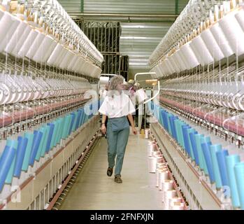 Sachsen-Anhalt / Industrie / DDR / Leuna 1995. Die DOMO Group (Carpets) hat ein neues Werk zur Herstellung von Teppichfasern errichtet. Das Foto zeigt die Spinnerei. Die Garne werden auf den Garnrollen aufgewickelt. Die Frauen müssen neue Rollen einlegen, das Garn fädeln und es greifen, wenn es zusammenbricht. Typische Frauenarbeit. Die Fabrik wurde auf dem alten VEB-Gelände gebaut, auf dem heute viele Unternehmen leben. Erfolgreich privatisiert von der Treuhand // Sachsen-Anhalt / Wirtschaft / Frauen / Textil / 1916 baut BASF aus Ludwigshafen eine Ammoniakfabrik in der Nähe des Dorfes Leuna. 1924 wird eine Methanolanlage zugesetzt und Stockfoto