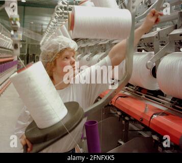 Sachsen-Anhalt / Industrie / DDR / Leuna 1995. Die DOMO Group (Carpets) hat ein neues Werk zur Herstellung von Teppichfasern errichtet. Das Foto zeigt die Spinnerei. Die Garne werden auf den Garnrollen aufgewickelt. Die Frauen müssen neue Rollen einlegen, das Garn fädeln und es greifen, wenn es zusammenbricht. Typische Frauenarbeit. Die Fabrik wurde auf dem alten VEB-Gelände gebaut, auf dem heute viele Unternehmen leben. Erfolgreich privatisiert von der Treuhand // Sachsen-Anhalt / Wirtschaft / Frauen / Textil / 1916 baut BASF aus Ludwigshafen eine Ammoniakfabrik in der Nähe des Dorfes Leuna. 1924 wird eine Methanolanlage zugesetzt und Stockfoto