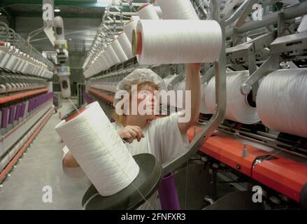 Sachsen-Anhalt / Industrie / DDR / Leuna 1995. Die DOMO Group (Carpets) hat ein neues Werk zur Herstellung von Teppichfasern errichtet. Das Foto zeigt die Spinnerei. Die Garne werden auf den Garnrollen aufgewickelt. Die Frauen müssen neue Rollen einlegen, das Garn fädeln und es greifen, wenn es zusammenbricht. Typische Frauenarbeit. Die Fabrik wurde auf dem alten VEB-Gelände gebaut, auf dem heute viele Unternehmen leben. Erfolgreich privatisiert von der Treuhand // Sachsen-Anhalt / Wirtschaft / Frauen / Textil / 1916 baut BASF aus Ludwigshafen eine Ammoniakfabrik in der Nähe des Dorfes Leuna. 1924 wird eine Methanolanlage zugesetzt und Stockfoto