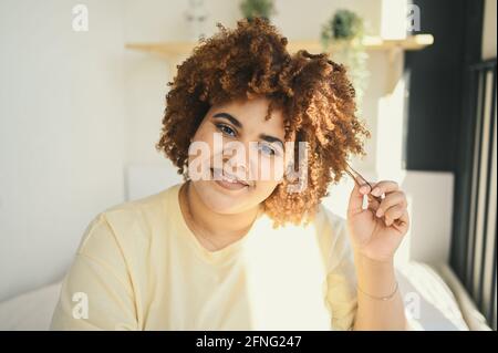 Nahaufnahme sonnig Porträt glücklich lächelnd kurvig plus Größe afrikanisch schwarz Frau afro Haar mit Make-up posiert in beige T-Shirt. Body Imperfection, Body Acceptance, Body positive und Diversity Konzept. Stockfoto