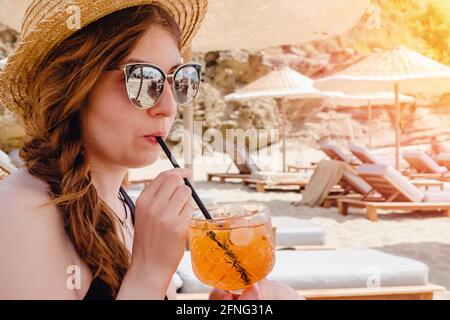 Frau mit Strohhut und Sonnenbrille trinkt aperol Spritz Stockfoto