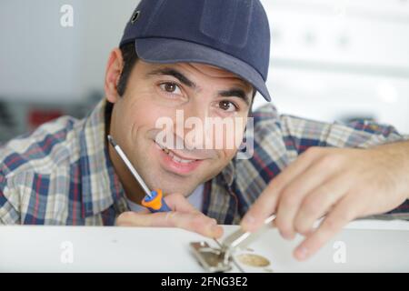 Casual Mann bohrt Nagel in Plank Stockfoto