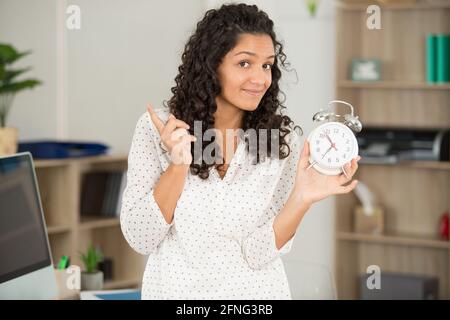 Frau mit Wecker im Bürozeitmanagement-Konzept Stockfoto