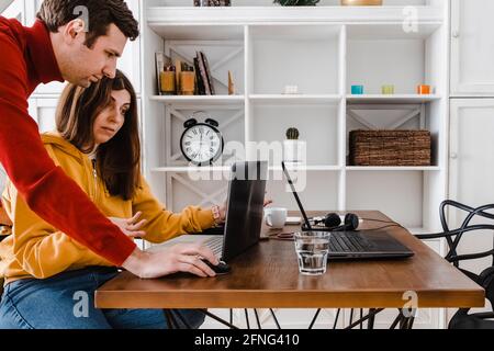 Überraschte Frau, die dem Mann etwas auf ihrem Bildschirm zeigte. Stockfoto