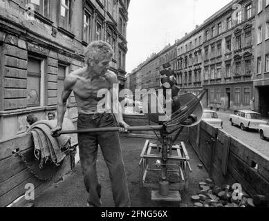 Sachsen / Orte / DDR-Land / Leipzig-Connewitz, 1990. Das Arbeiterviertel war sehr verfault und sollte nach Plänen der DDR teilweise abgerissen werden. Das Foto zeigt eine Gründerzeit Straße und den Koalman. Er liefert in den Keller. Es war üblich, die Kohlen einfach auf die Straße zu schaufeln. Foto: Kohle wird in den Kalkübel geschaufelt. Der Eimer wird dann gekippt und die Kohlen gleiten in einen Sack. // Braunkohle / Energie / Kohle / Arbeit / KW / Bundesländer / [automatisierte Übersetzung] Stockfoto