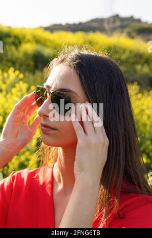 Junge Hündin in roter Kleidung und Sonnenbrillen blicken hinein Hintergrundbeleuchtung Stockfoto