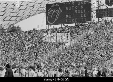 „Fans beim Rolling Stones Konzert in den Zuschauerreihen im Olympiastadion in München. Im Hintergrund ist ein großes Brett mit der Aufschrift ''ITS only Rock n Roll, but we like it'' und dem typischen Mund der Band mit der Zunge, die herausragt. [Automatisierte Übersetzung]' Stockfoto