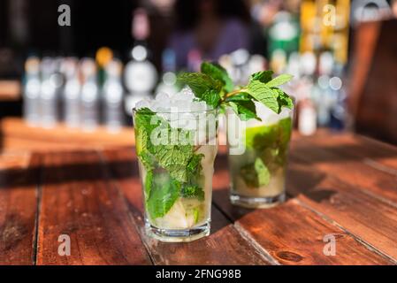Es werden erfrischende Mojito-Cocktails mit Eis und Minze serviert An der Holztheke im Freien Stockfoto