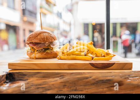 Köstlicher, frischer Hamburger und knusprige Pommes Frites auf Holz Gehen Sie an Bord in einem modernen Fast-Food-Restaurant Stockfoto
