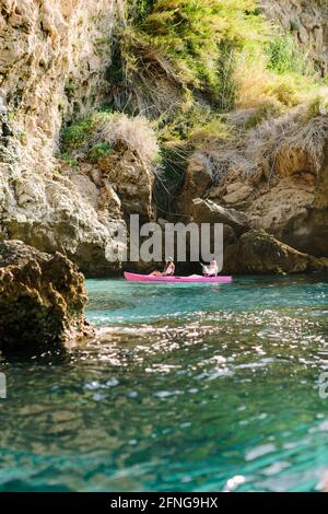 Seitenansicht Reisende mit Paddeln schwimmend auf türkisfarbenem Meerwasser in der Nähe Die felsige Küste an sonnigen Tagen in Malaga Spanien Stockfoto