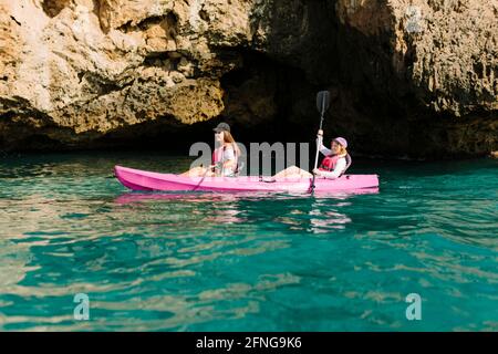 Seitenansicht Reisende mit Paddeln schwimmend auf türkisfarbenem Meerwasser in der Nähe Die felsige Küste an sonnigen Tagen in Malaga Spanien Stockfoto