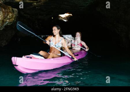 Seitenansicht Reisende mit Paddeln schwimmend auf türkisfarbenem Meerwasser in der Nähe Die felsige Küste an sonnigen Tagen in Malaga Spanien Stockfoto