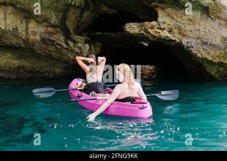 Rückansicht Reisende mit Paddeln, die in der Nähe auf türkisfarbenem Meerwasser schweben Die felsige Küste an sonnigen Tagen in Malaga Spanien Stockfoto