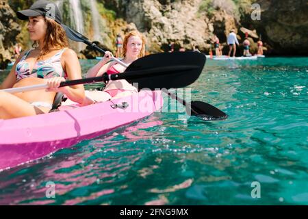 Seitenansicht Reisende mit Paddeln schwimmend auf türkisfarbenem Meerwasser in der Nähe Die felsige Küste an sonnigen Tagen in Malaga Spanien Stockfoto