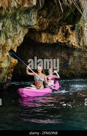 Seitenansicht Reisende mit Paddeln schwimmend auf türkisfarbenem Meerwasser in der Nähe Die felsige Küste an sonnigen Tagen in Malaga Spanien Stockfoto