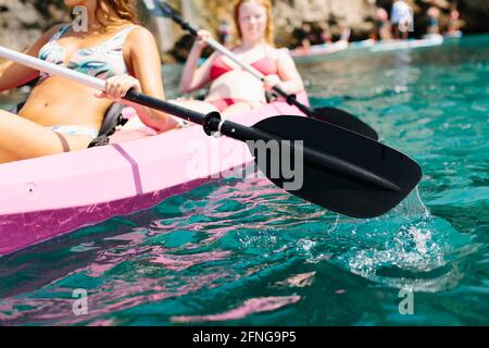 Seitenansicht Reisende mit Paddeln schwimmend auf türkisfarbenem Meerwasser in der Nähe Die felsige Küste an sonnigen Tagen in Malaga Spanien Stockfoto