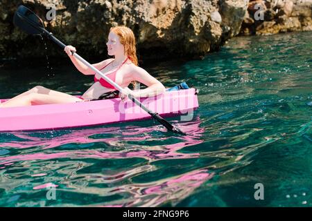 Seitenansicht Reisende mit Paddeln schwimmend auf türkisfarbenem Meerwasser in der Nähe Die felsige Küste an sonnigen Tagen in Malaga Spanien Stockfoto