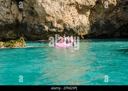 Seitenansicht Reisende mit Paddeln schwimmend auf türkisfarbenem Meerwasser in der Nähe Die felsige Küste an sonnigen Tagen in Malaga Spanien Stockfoto