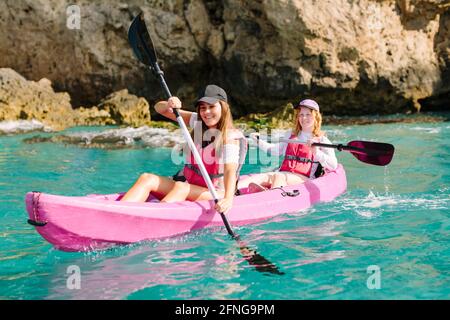 Seitenansicht Reisende mit Paddeln schwimmend auf türkisfarbenem Meerwasser in der Nähe Die felsige Küste an sonnigen Tagen in Malaga Spanien Stockfoto