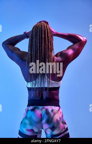 Rückansicht einer anonymen muskulösen afroamerikanischen Athletin mit Verschwitzter Körper mit Bizeps auf blauem Hintergrund Stockfoto
