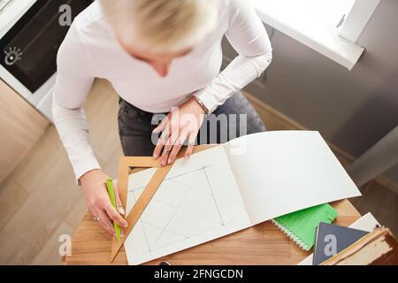 Von oben der Ernte nicht erkennbare weibliche Astrologen Zeichnung auf Papier Mit Dreieck und Stift am Tisch Stockfoto