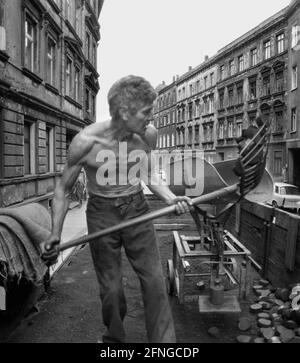 Sachsen / Orte / DDR-Land / Leipzig-Connewitz, 1990. Das Arbeiterviertel war sehr verfault und sollte nach Plänen der DDR teilweise abgerissen werden. Das Foto zeigt eine Gründerzeit Straße und den Koalman. Er liefert in den Keller. Es war üblich, die Kohlen einfach auf die Straße zu schaufeln. Foto: Kohle wird in den Kalkübel geschaufelt. Der Eimer wird dann gekippt und die Kohlen gleiten in einen Sack. // Braunkohle / Energie / Kohle / Arbeit / KW / Bundesländer / [automatisierte Übersetzung] Stockfoto