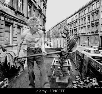 Sachsen / Orte / DDR-Land / Leipzig-Connewitz, 1990. Das Arbeiterviertel war sehr verfault und sollte nach Plänen der DDR teilweise abgerissen werden. Das Foto zeigt eine Gründerzeit Straße und den Koalman. Er liefert in den Keller. Es war üblich, die Kohlen einfach auf die Straße zu schaufeln. Foto: Kohle wird in den Kalkübel geschaufelt. Der Eimer wird dann gekippt und die Kohlen gleiten in einen Sack. // Braunkohle / Energie / Kohle / Arbeit / KW / Bundesländer / [automatisierte Übersetzung] Stockfoto