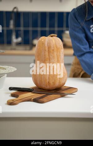 Crop unkenntlich Weibchen am Tisch mit frischem Squash und Messer Auf dem Schneidebrett in der Hausküche Stockfoto