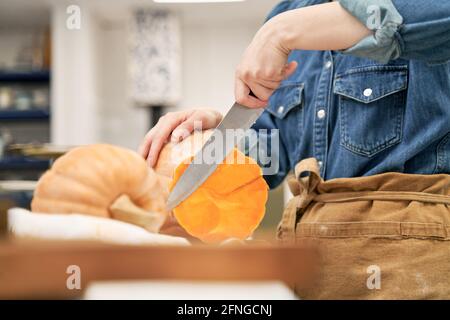 Crop weiblich mit scharfen Messer schneiden rohen Squash beim Schneiden Gehen Sie an Bord, während Sie in der Küche zu Hause kochen Stockfoto