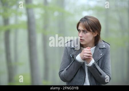 Verängstigte Frau, die allein in einem nebligen Wald auf die Kamera zugeht Stockfoto