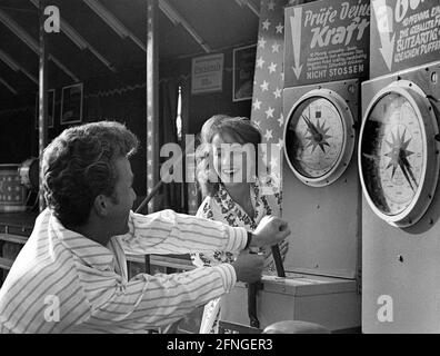 Der Mann beeindruckt eine Dame, indem er seine Macht zeigt Ein Messegelände Verkaufsautomat [automatisierte Übersetzung] Stockfoto