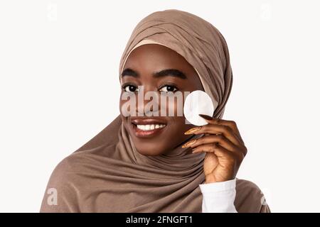 Portrait einer muslimischen schwarzen Frau, die die Haut mit einem Wattepad reinigt Stockfoto