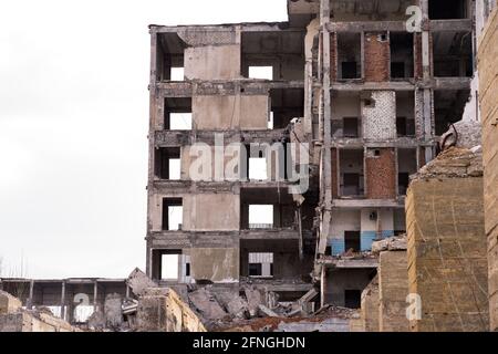 Ein zerstörter Bau vor einem trüben grauen Himmel mit großen Fundamentstapeln im Vordergrund. Hintergrund. Stockfoto