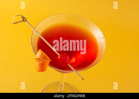 Traditioneller Manhattan Cocktail mit Kirsche auf gelbem Hintergrund Stockfoto